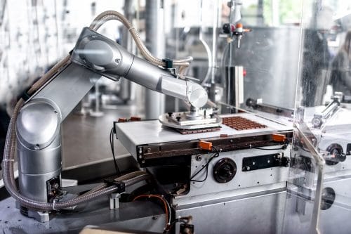 automatic robotic hand moving and preparing bits of chocolate